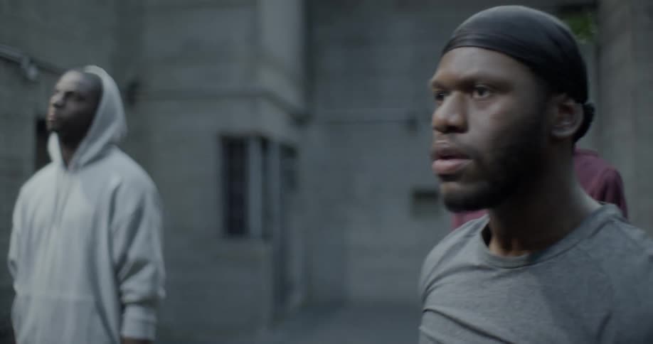 Three men in a concrete room look on in disbelief
