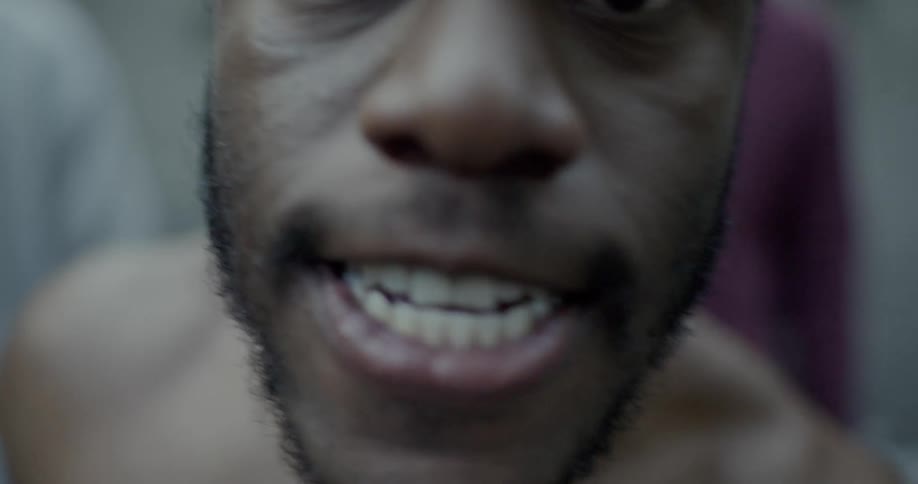 A black man yells at someone as others stand and watch
