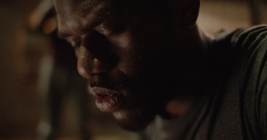 A black man looks down in concentration