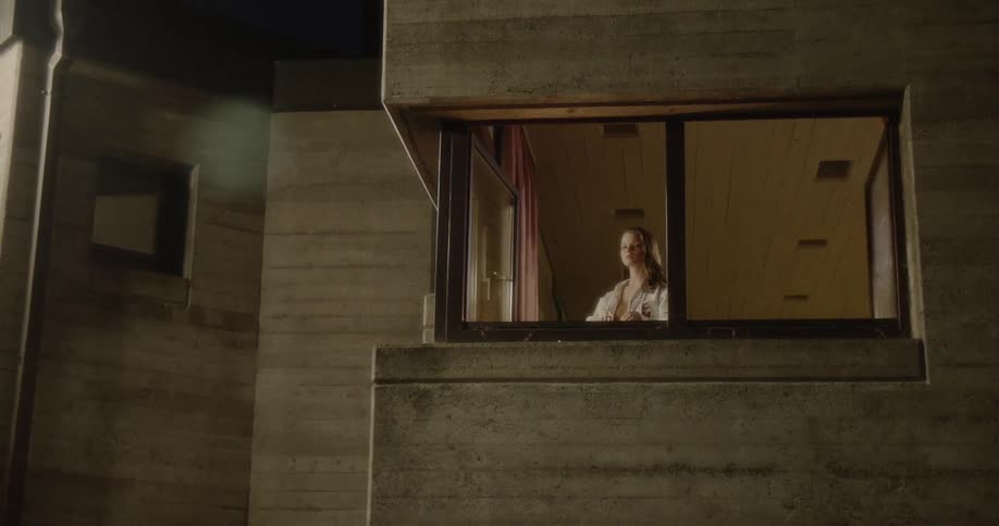 A teenage boy catches a basketball thrown at him when a girl walks to an upper window to watch