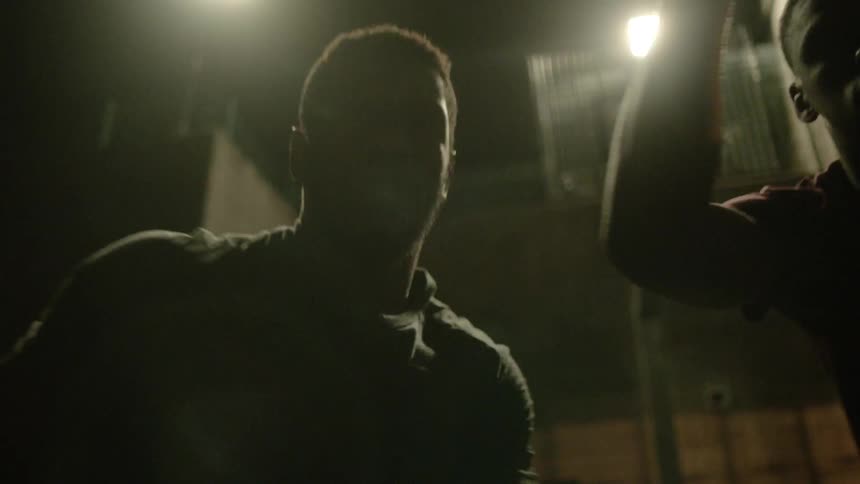 Men play basketballin dark area under lights
