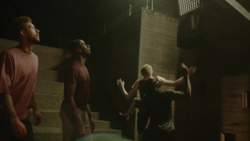 A group of four men play basketball together