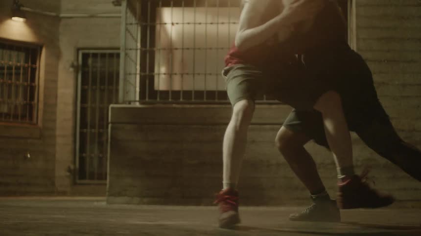Young men playing basketball in street at night
