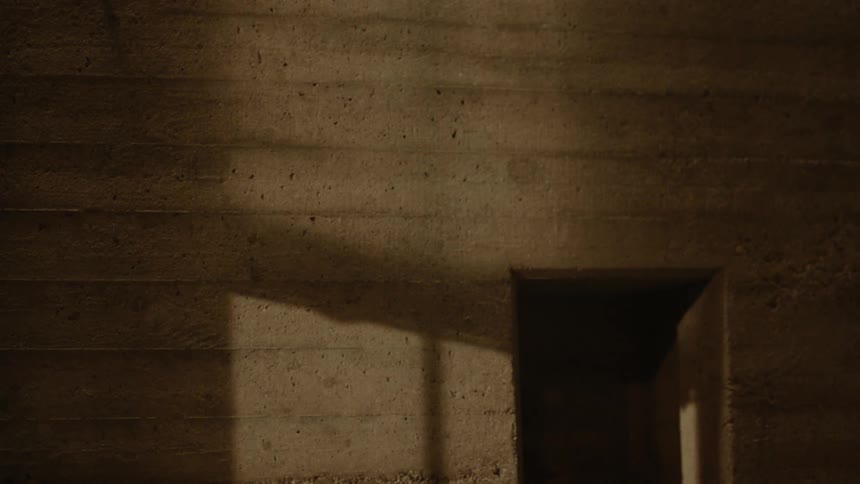 Person casts shadows as they run past opening in wall