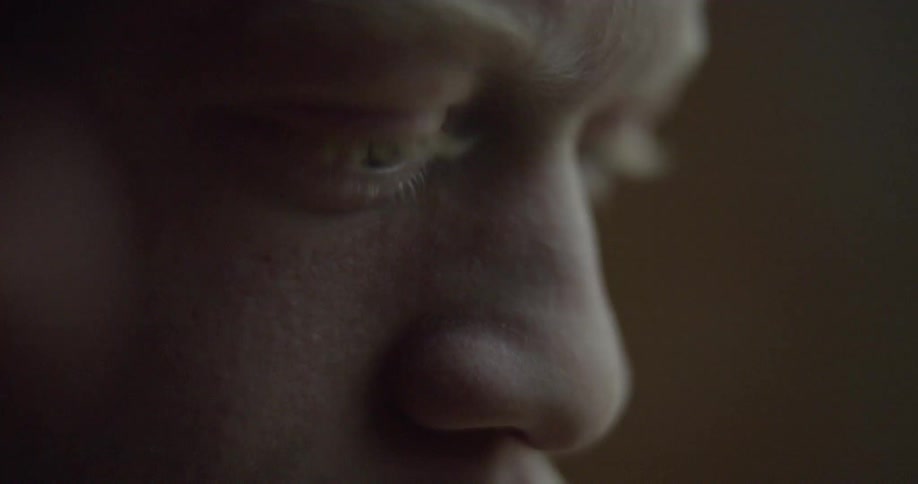 A young man looks down and blinks