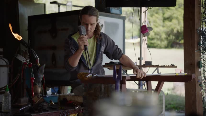 A man is spinning glass outside