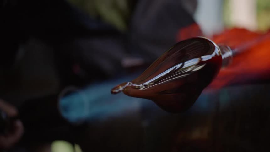 Person applies torch to rotated glass shape