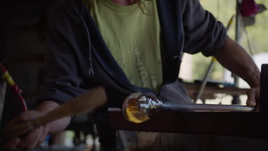 Man brushes off a round glass craft