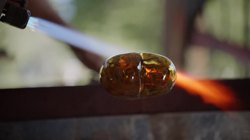 A glassblower uses a blowtorch on a project