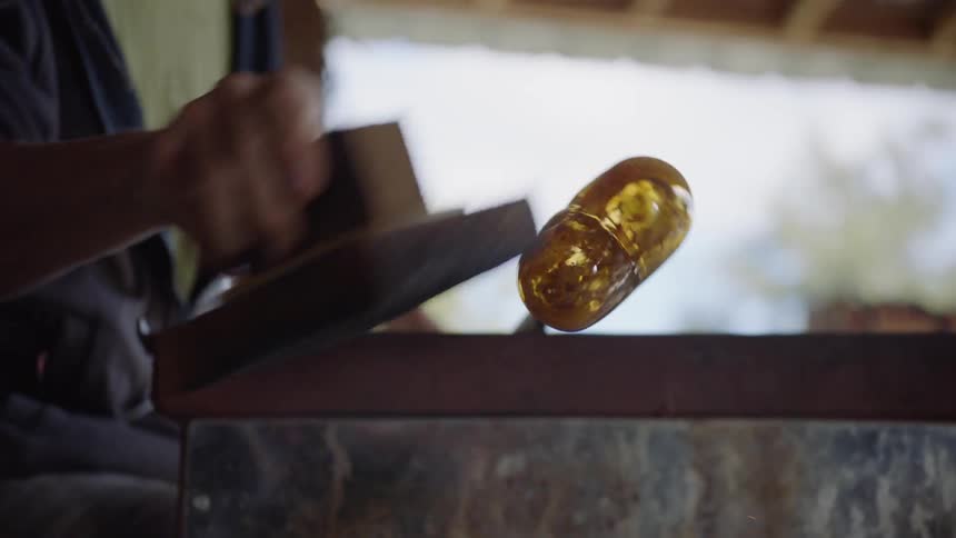 A man sands a piece of newly made glass