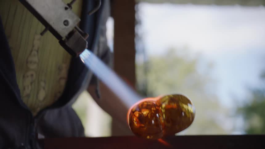 A man blows a torch on glass