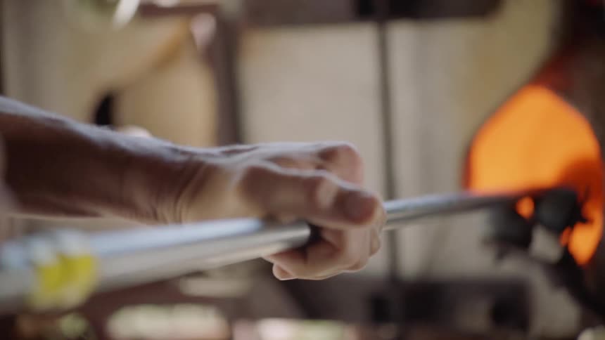 A man heats glass for glass blowing