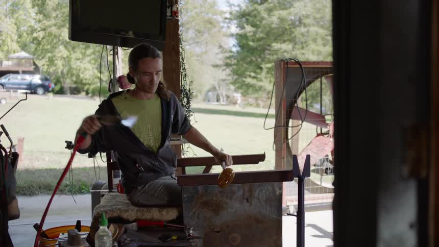 A glass blower heats up glass