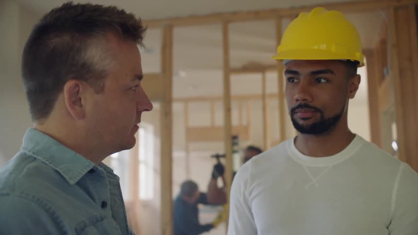 Two men talk to each other while standing in a new construction home