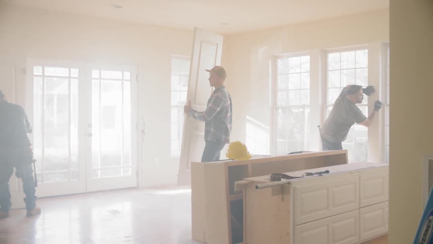 Multiple construction employees work inside the interior of a home