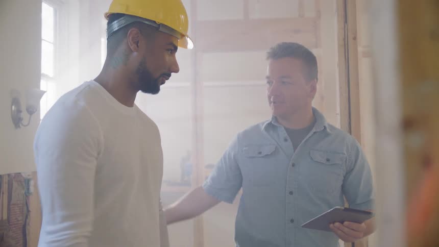 Two men shake hands on a construction site