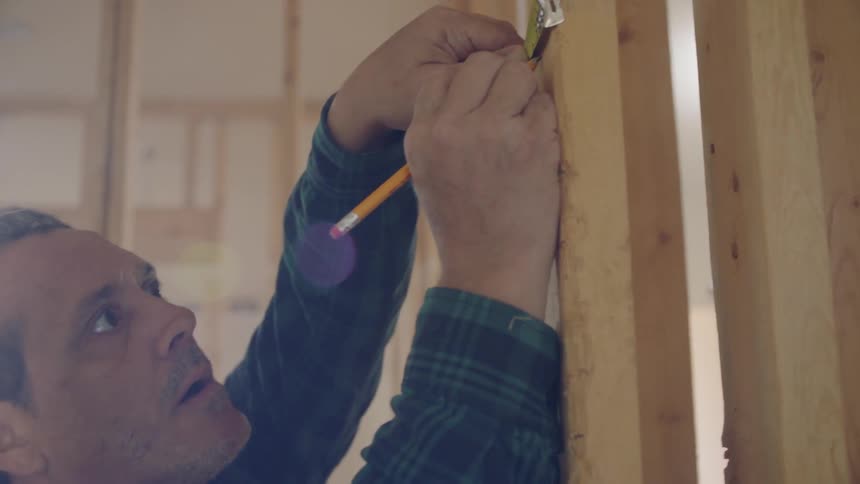 A carpenter is measuring a wooden beam