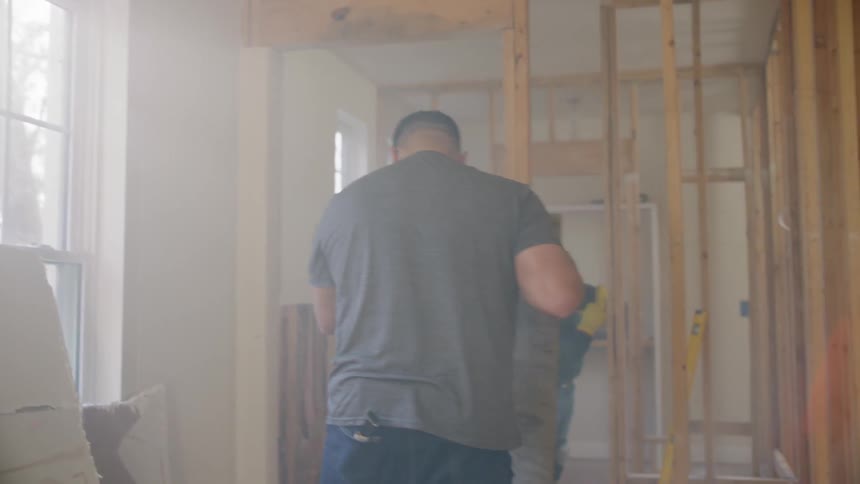 A construction worker picks up sheetrock on a construction site