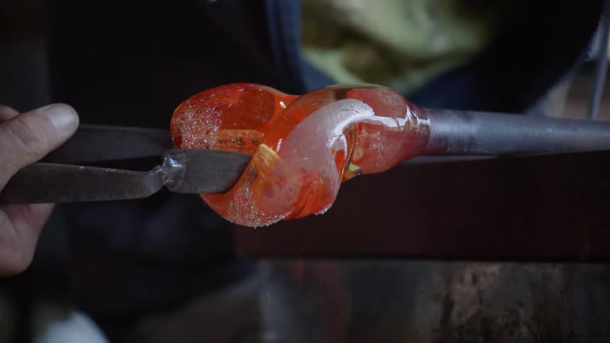 Person working molten glass into shape