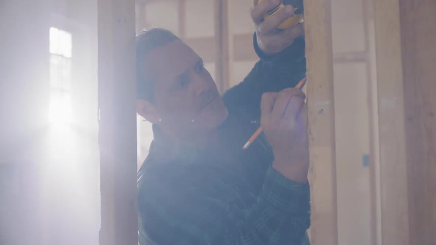 Contractor taking measurements on framed structure