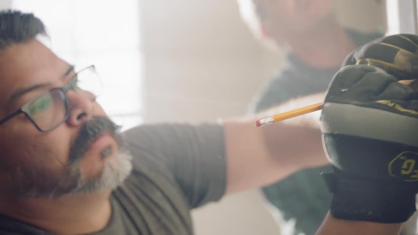 A white man writes on a wall as another man watches