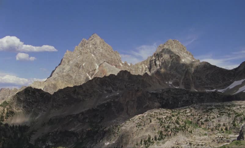 A steep mountain range dotted with pine trees