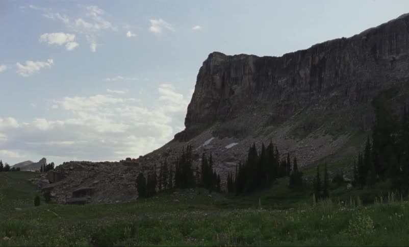 Mountain towers over grassy plain under a slightly cloudy sky