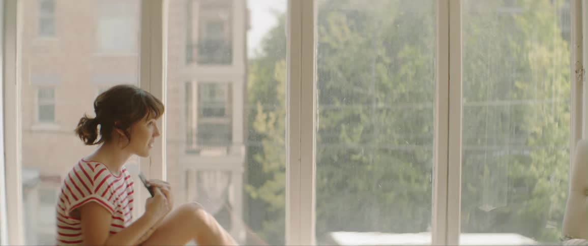 Young woman sitting near a window talking on her cell phone