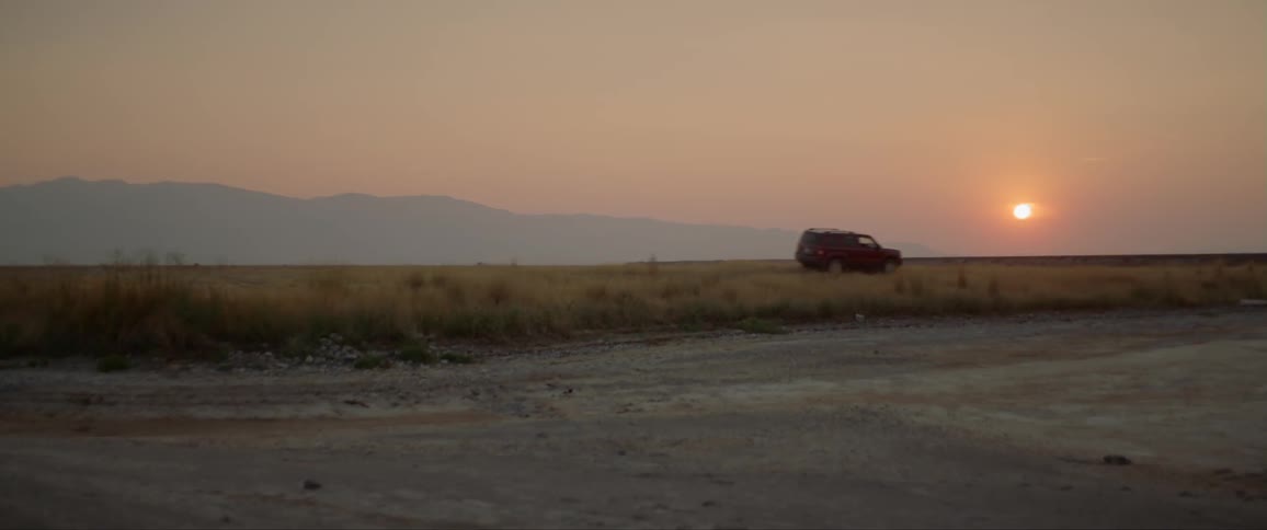 An suv travels past on a road at sunset