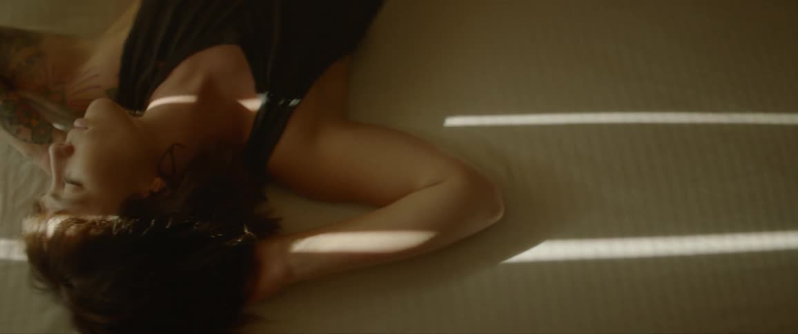 Tattooed woman lays in bed