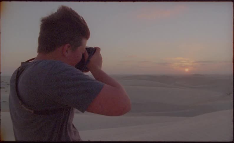 Man takes picture of setting sun setting on horizon over desert