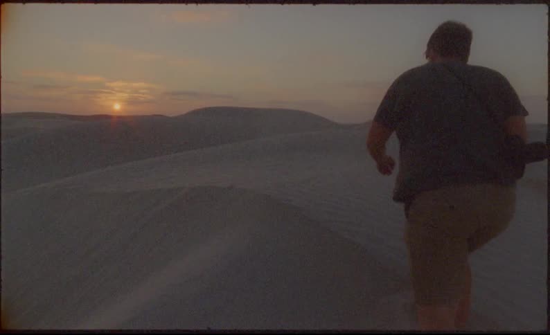 Man walks up on a sand dune