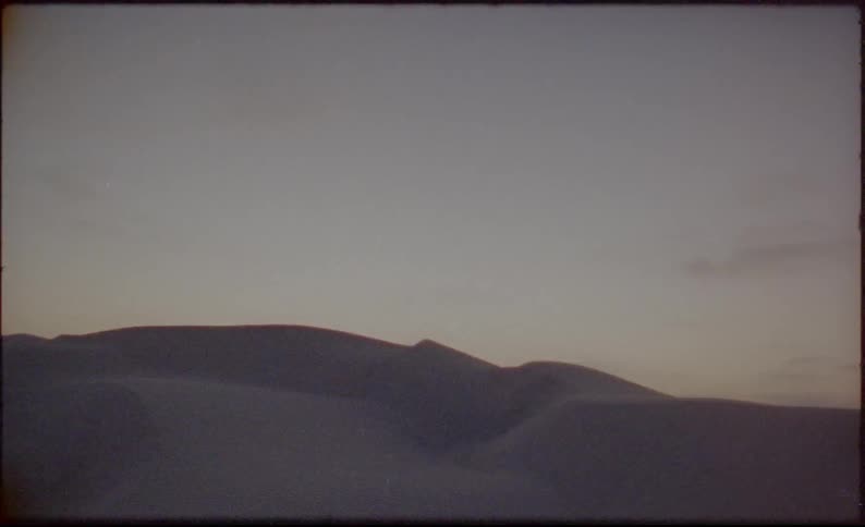 Slope bordered by hills under lightly cloudy sky