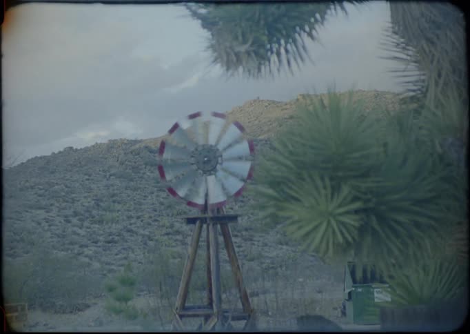 A windmill spins at the bottom of a hill