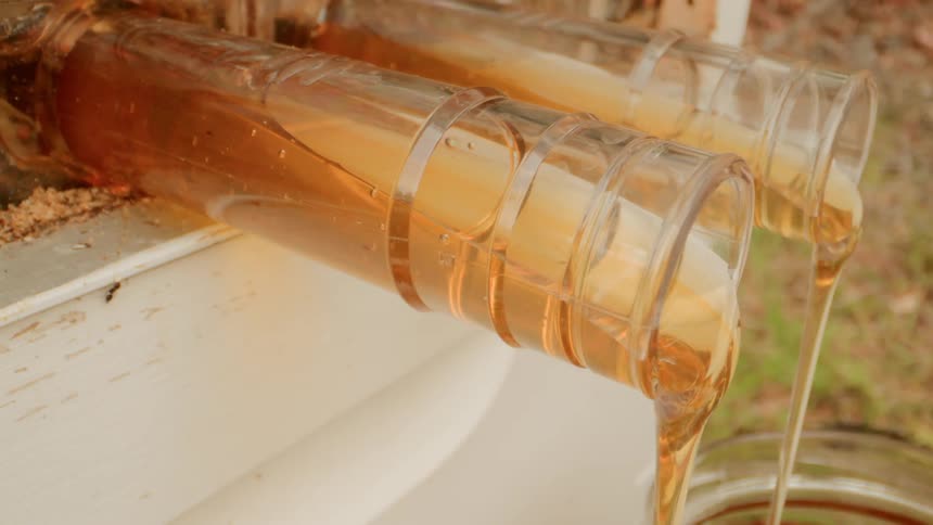 The honey is slowly pouring from the glass tubes