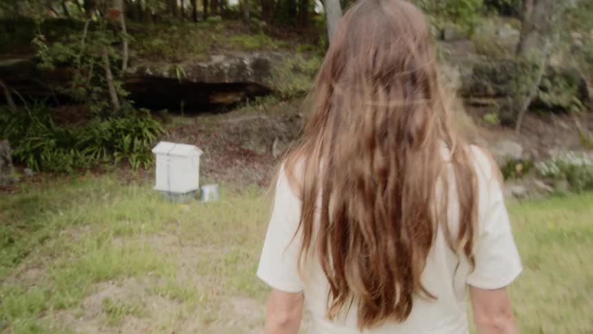 A woman is walking towards the bee hive on the farm