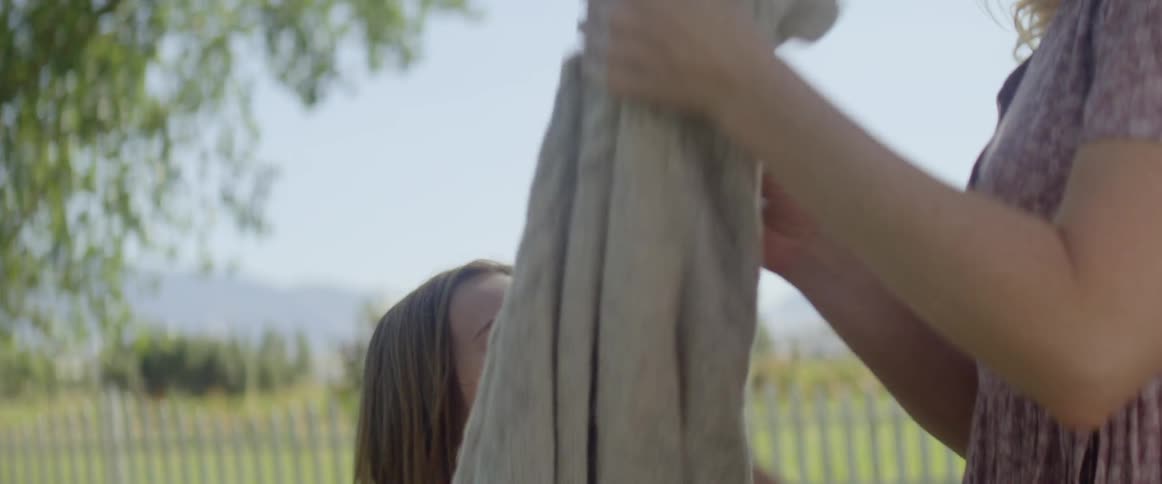 Child runs toward mother carrying laundry basket outdoors