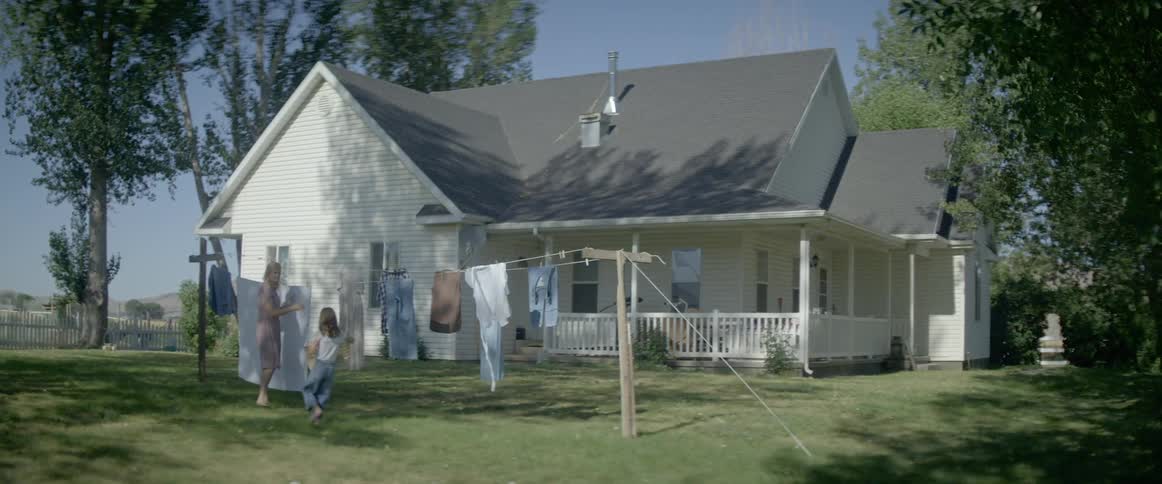 A child runs to her mother with a laundry basket in the yard