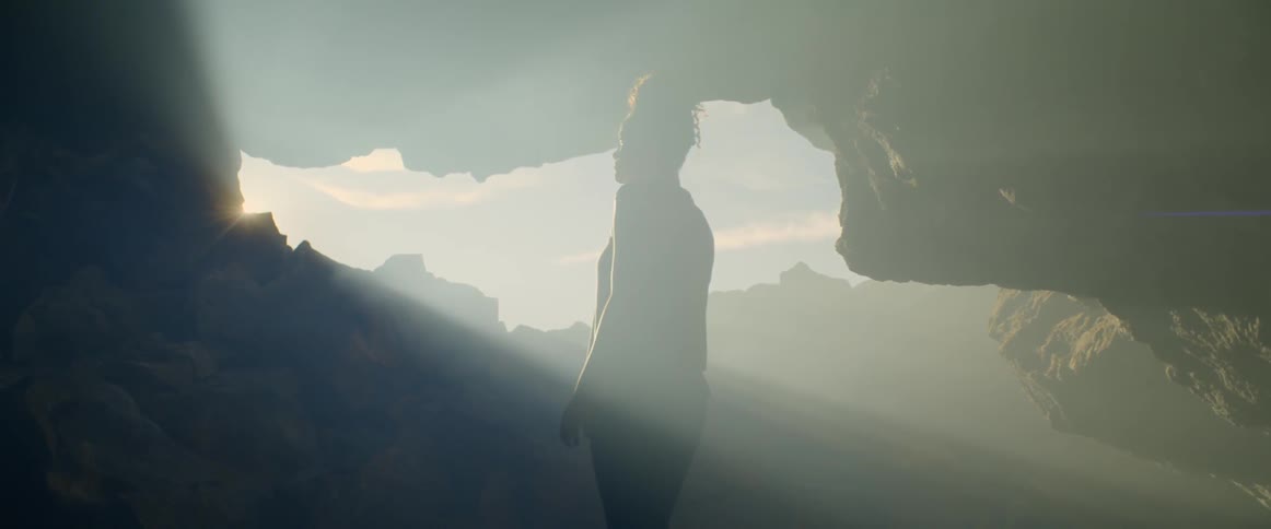 Sunlight shining through an opening in a cave on to a young woman standing within