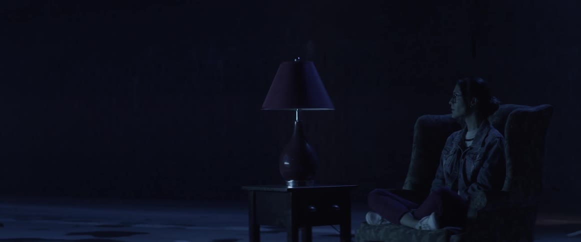 A woman is sitting on a chair outside at night