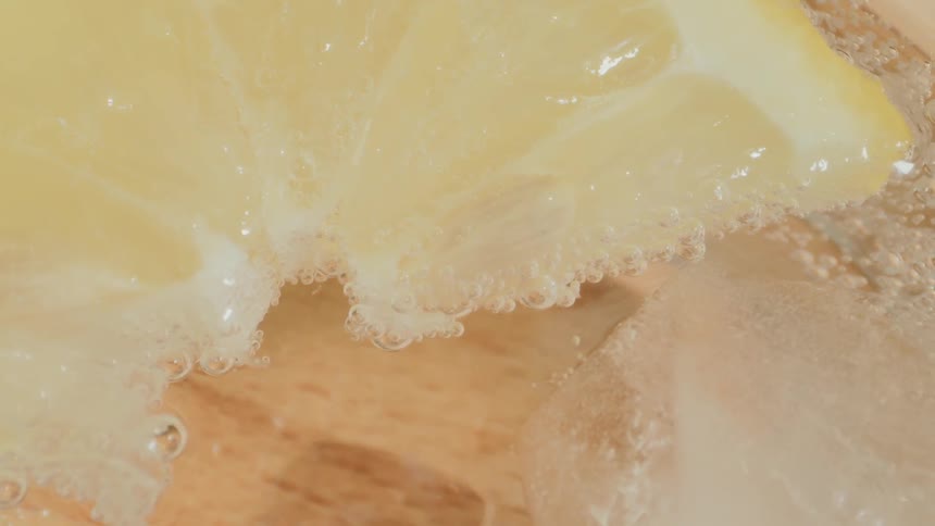 A lemon wedge floats in a carbonated liquid