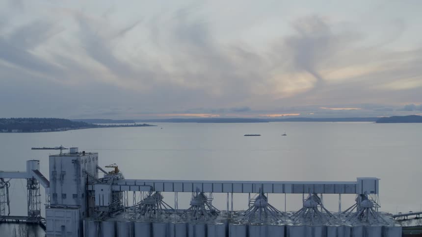 Pullback reveal of a bulk grain shipping terminal on the edge of the water