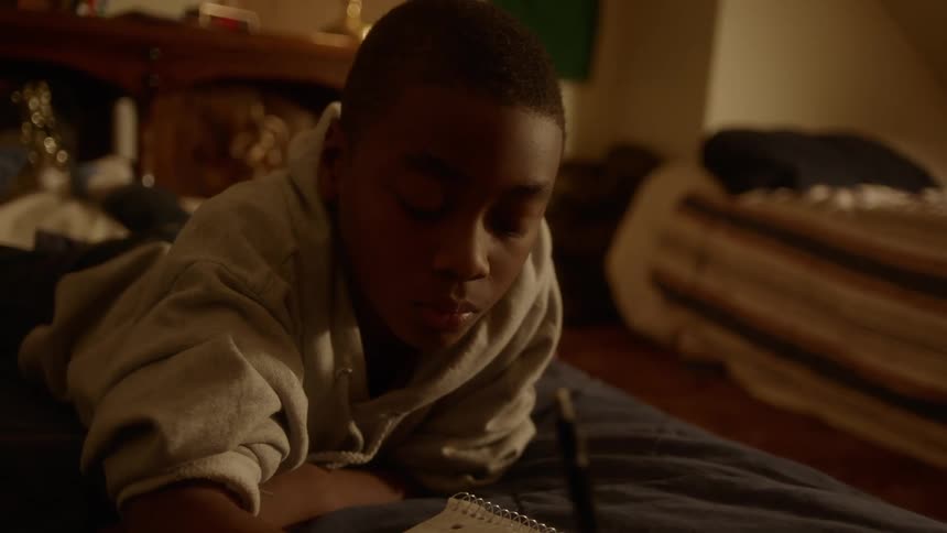A boy writes in a notebook