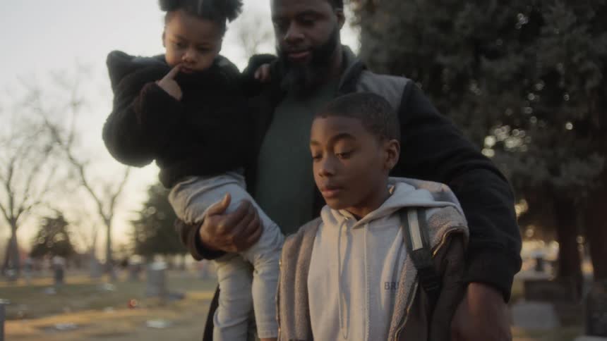 Family stands grieving in graveyard