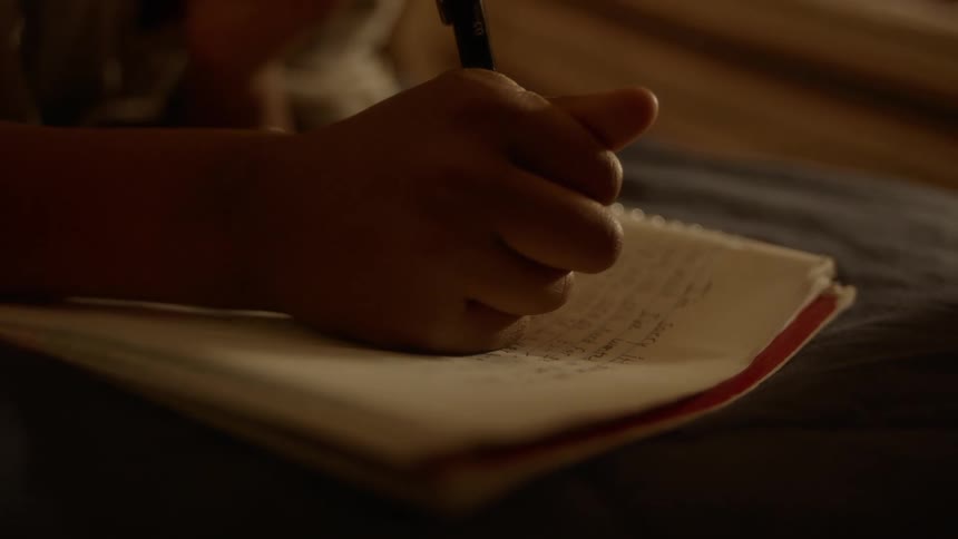 A person writes in a notebook