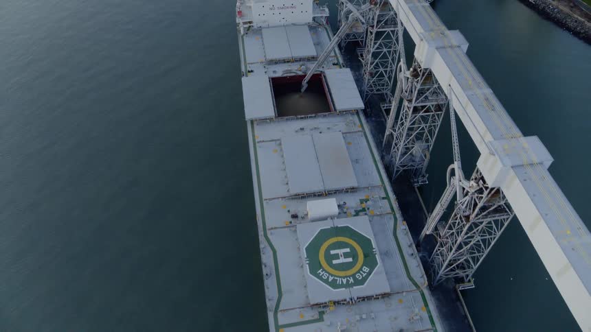 Overhead view of grain being transferred into a bulk cargo ship