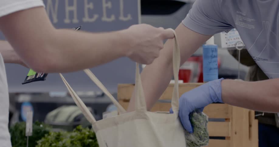 A person buys kale at a farmers market