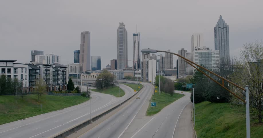 A few vehicles drive along roads leading towards and away from a city filled with tall buildings
