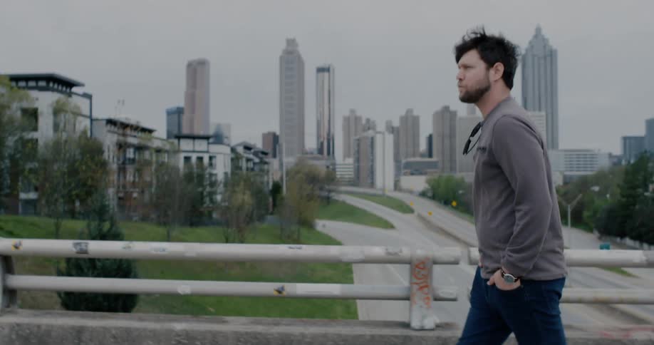 A man is walking on a bridge in a downtown area