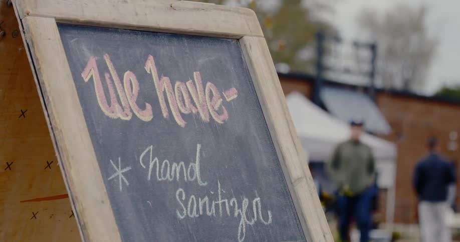 A chalk board sign advertising the availability of hand sanitizer